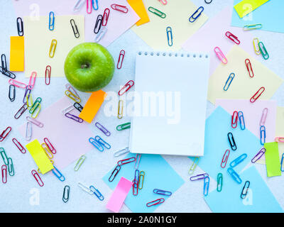 Apple, Notepad, paper clips, stickers on the table Stock Photo