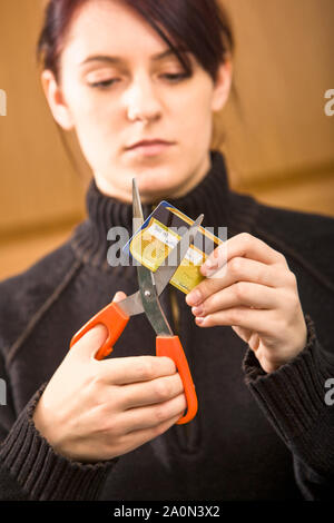 Cutting up credit card. Young woman using scissors to cut. Stock Photo