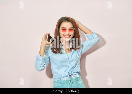 Portrait happy summer mood of joyful young woman with long curly hair, in sunglasses on light background. Blue colors, expressing positivity, music, j Stock Photo