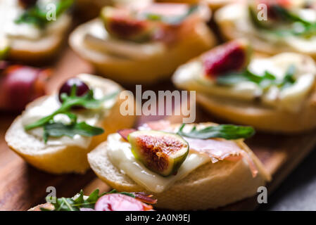 Traditional tapas from spain or italian bruschetta with cheese, meat and figs. Party food on catering platter. Stock Photo