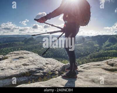 Tourist photograper hiking on mountain trail, walking on sandstone rocky hill, wearing backpack and sunglasses, using equipment. Stock Photo