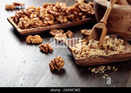 Walnuts in a wooden dish on an old wooden table. Crushed and whole nuts near the mortar. Stock Photo