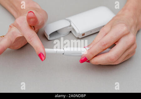 cigarette inserts Woman's hands holds an electronic cigarette. Insert a cigarette into the  mouthpiece. Smoking, health, struggle, addiction Stock Photo
