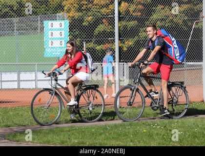 young couple cycling between the courts of  their tennis club Stock Photo
