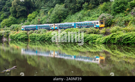Cardiff, Wales, UK - July 19, 2019: A pair of 2-car Pacer passenger trains runs along the green banks of the River Taff at Radyr in the suburbs of Car