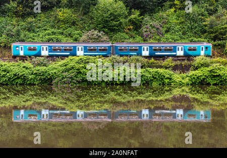 Cardiff, Wales, UK - July 19, 2019: A 2-car Sprinter passenger train runs along the green banks of the River Taff at Radyr in the suburbs of Cardiff. Stock Photo