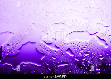 Wet glass in drops of water or rain, bright purple color, studio light, gradient, wet mirror surface texture background close up Stock Photo