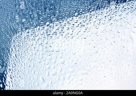 Many small drops of water glass surface, window in the raindrops, mirror in the drops of condensate water in bright blue color, abstract design Stock Photo