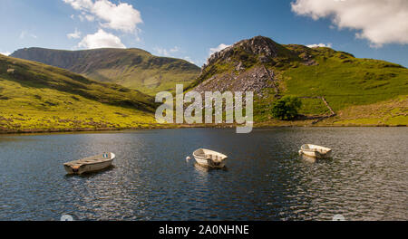 Three traditional rowing boats are moored in Llyn y Dywarchen, a small reservoir and fishing lake near Rhy-Ddu in Snowdonia National Park, North Wales Stock Photo