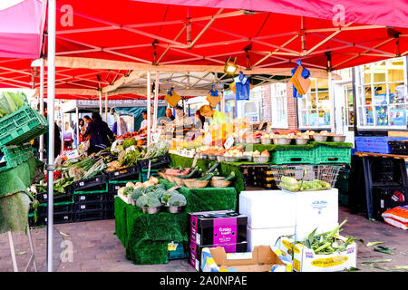 Market Trader Selling Fresh Fruit and Vegetables, Including Broccoli, Potatoes, Tomatoes and Sweet Corn Stock Photo