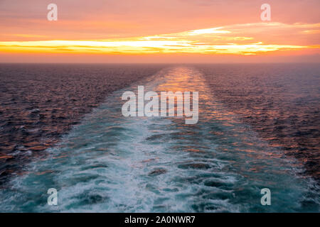 Sunset over the North Sea, and ships wake disappearing into the distance, from the Queen Mary 2 Stock Photo