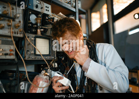 Crazy scientist works with electricity in lab Stock Photo