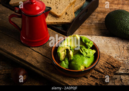 Avocado slices in a rustic bowl and bread for a healthy sandwich Stock Photo