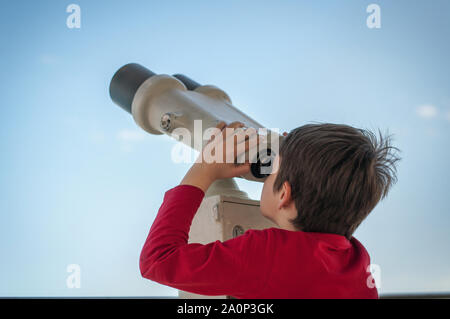 the boy looks through a tourist telescope at the sky Stock Photo