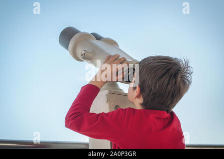 the boy looks through a tourist telescope at the sky Stock Photo
