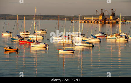 Holyhead, Wales, UK - June 15, 2009: Small yachts are moored in Holyhead Harbour, beside a large industrial pier. Stock Photo