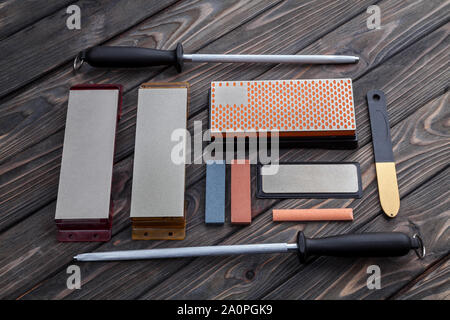 A variety of knife sharpeners. Sharpening stones and devices on a wooden background. Grinding stones Stock Photo