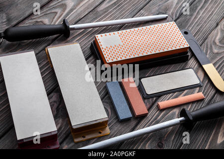 A variety of knife sharpeners. Sharpening stones and devices on a wooden background. Grinding stones Stock Photo