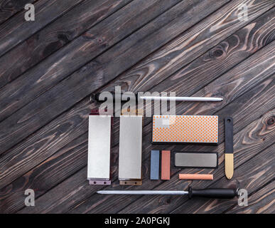 A variety of knife sharpeners. Sharpening stones and devices on a wooden background. Grinding stones Stock Photo