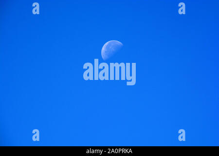 Half Moon During Day in clear Blue Sky, waning moon at daytime azure sky background with copy space Stock Photo