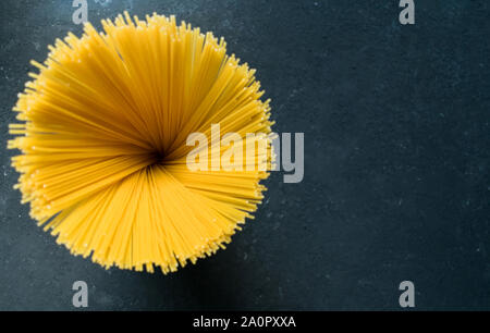 Yellow long spaghetti on a black background. Yellow Italian pasta. Raw spaghetti. Top view. Italian food and menu concept. Copy space. Stock Photo