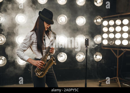 Female jazz musician in hat plays the saxophone Stock Photo