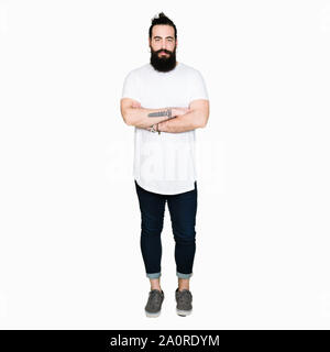 Young hipster man with long hair and beard wearing casual white t-shirt skeptic and nervous, disapproving expression on face with crossed arms. Negati Stock Photo