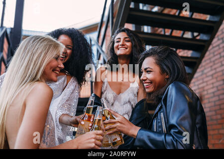 Beautiful laughing friends toasting with bottles of beer outdoors Stock Photo