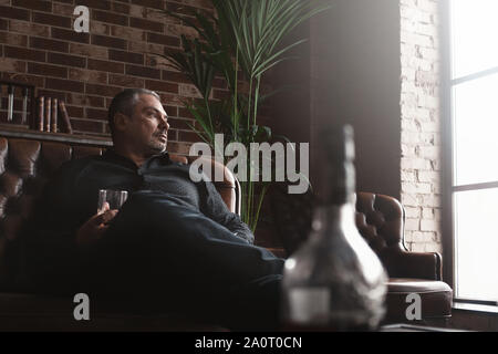 Relaxing after a hard working day. Confident mature businessman sitting at the bar and drinking whiskey Stock Photo