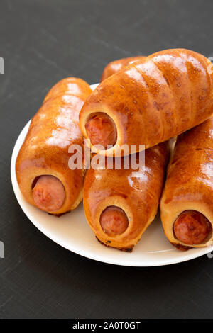 Homemade beef sausage kolache on a white plate on a black surface,  side view. Close-up. Stock Photo