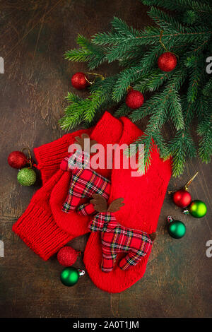 Christmas warm knitted red socks with toy deers. Christmas background with gifts. Top view, flat lay. Stock Photo