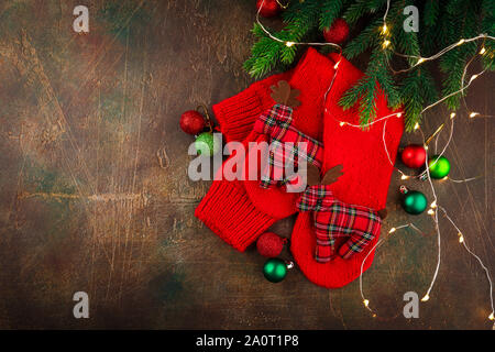 Christmas warm knitted red socks with toy deers. Christmas background with gifts. Copy space, top view, flat lay. Stock Photo