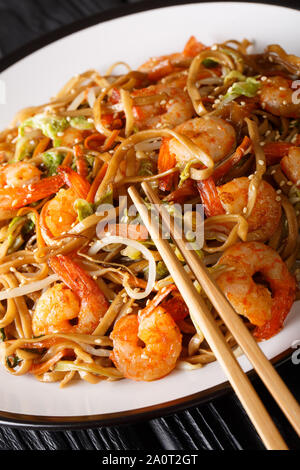 Close-up fried chow mein noodles with shrimp and vegetables classic recipe on a plate on the table. vertical Stock Photo