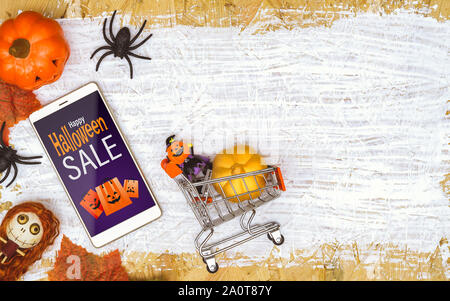 Happy Halloween Sale supermarket shopping  background concept, smartphone mockup with shopping cart flat lay design. Stock Photo