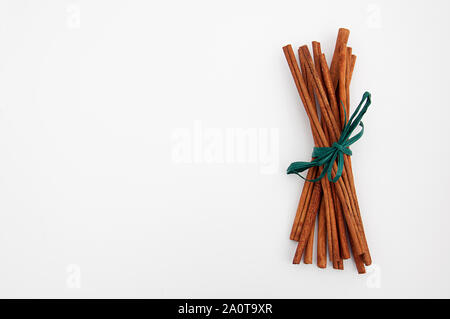 Cinnamon sticks with green raffia ribbon still life isolated on light background with plenty of room for custom text. Stock Photo