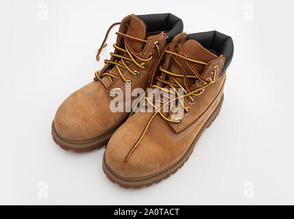 Pair of hiking boots tan colored with boot laces untied, isolated on light background. Stock Photo
