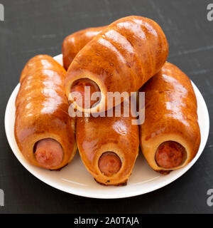 Homemade beef sausage kolache on a white plate on a black background, side view. Close-up. Stock Photo