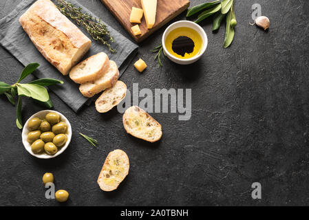 Ciabatta. Fresh italian ciabatta bread with herbs, olive oil, parmesan and olives on black background, top view, copy space. Italian food. Stock Photo