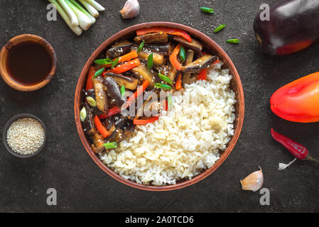 Stir fried eggplant and bell pepper and rice on white, top view, copy space. Asian chinese food. Vegan healthy meal and ingredients. Stock Photo