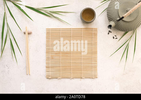 Asian food background - green tea, teapot and chopsticks with bamboo mat and leaves on white background, copy space. Asian menu design, chinese japane Stock Photo