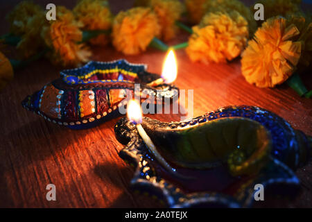 Set of two colorful design diyas (light lamps) lightened during festival of Diwali with yellow marigold flower background Stock Photo
