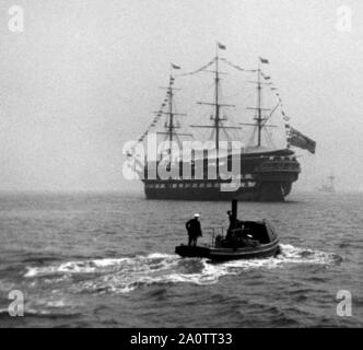 AJAXNETPHOTO. 1900S. PORTSMOUTH, ENGLAND. - DRESSED OVERALL - AN OLD WOODEN WALL WARSHIP, PERHAPS HMS IMPLACABLE, A RELIC OF THE FRENCH NAVY THAT FOUGHT AT TRAFALGAR, DRESSED OVERALL IN PORTSMOUTH HARBOUR AS A STEAM PINNACE MAKES ITS WAY ACROSS HARBOUR.  PHOTO:AJAX VINTAGE PICTURE LIBRARY REF:()AVL NA IMPLACABLE 1900S Stock Photo