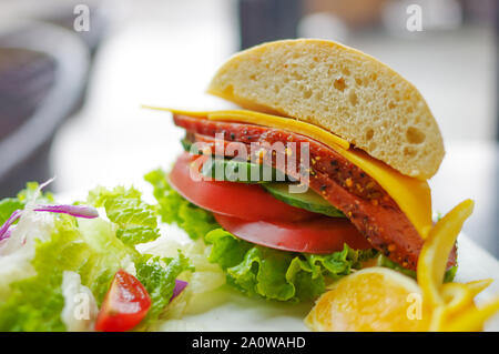 Sandwich with corned beef, cheese,  tomato, cucumber, lettuce salad and orange slices on white plate Stock Photo