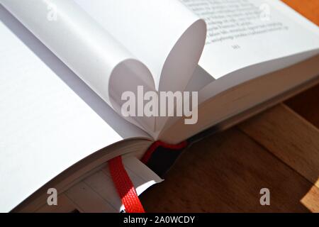 Love of books, reading/ Open book with curled leaves in the shape of a heart. Library, education Stock Photo