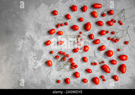 Red ripe tomatoes of different varieties and different sizes on a gray background. Minimalism. Stock Photo