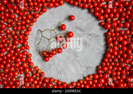 Round frame of cherry tomatoes on a gray background. Flat lay. Copy space. Stock Photo
