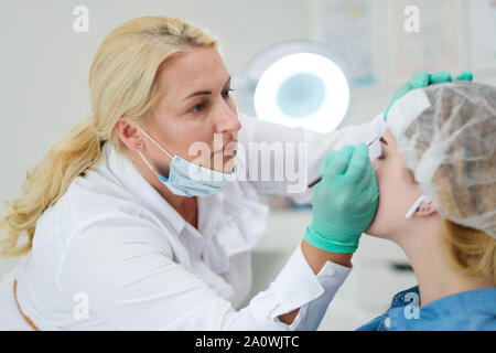 Makeup artist applies paint henna on eyebrows in a beauty salon Stock Photo