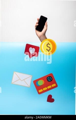 cropped view of man holding smartphone and paper icons falling down Stock Photo