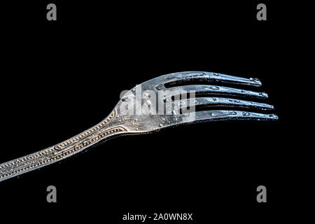 Single fork at the black table with water droplets on it. Stock Photo