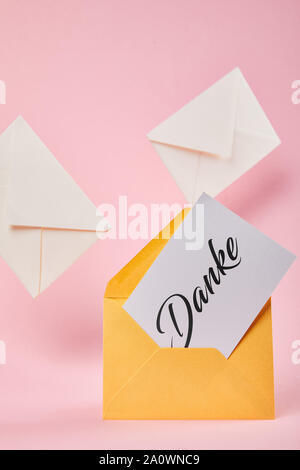 yellow envelope with danke word on white card near letters on pink background Stock Photo